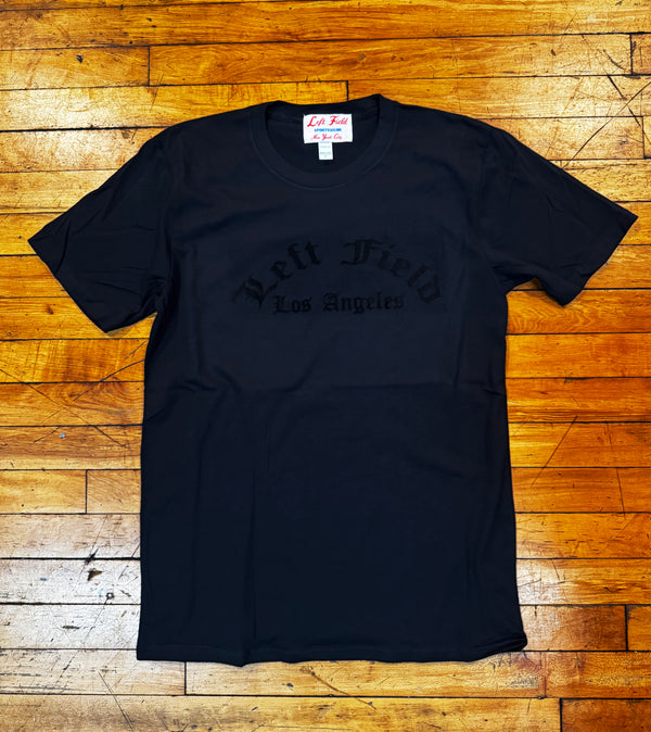 Black t-shirt with text on a wooden floor