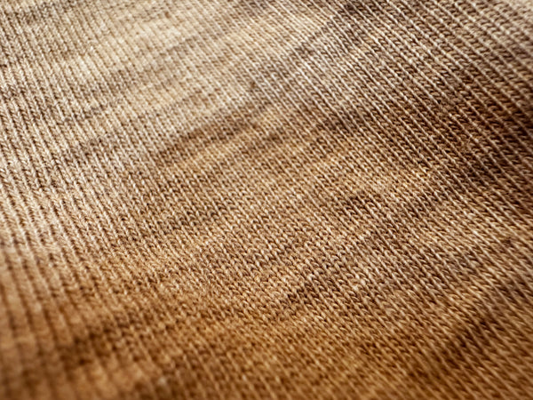Close-up of a brown knit fabric texture with a fine ribbed pattern and soft gradient shading.