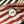 A close-up of a white button sewn onto striped fabric with red, navy, black, and beige horizontal bands.