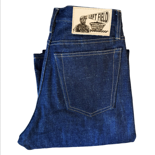 Folded blue denim jeans with a 'LEFT FIELD' label on a white background