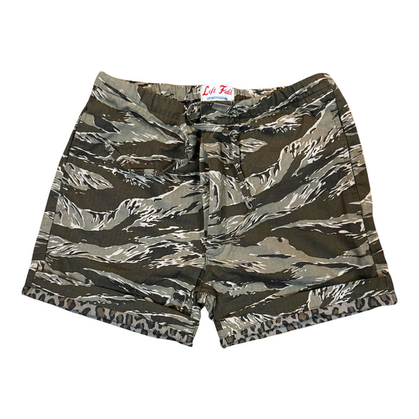A pair of camouflage print shorts with a tiger-stripe pattern in shades of green, brown, gray, and black, featuring a drawstring waist and a leopard-print hem, shown flat on a white background.